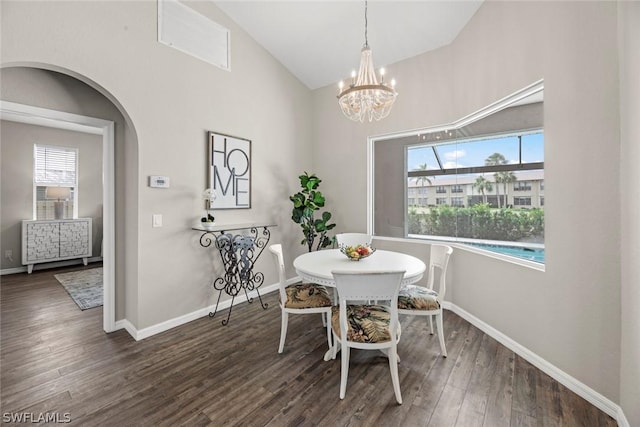 dining area with vaulted ceiling, dark wood-type flooring, and a notable chandelier