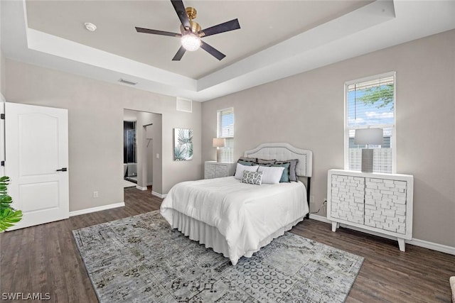 bedroom with a raised ceiling, ceiling fan, and dark hardwood / wood-style flooring