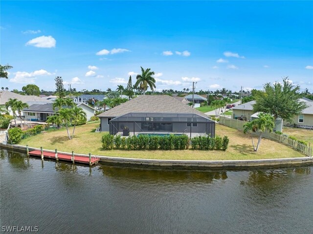 rear view of property with a water view, a lanai, and a lawn