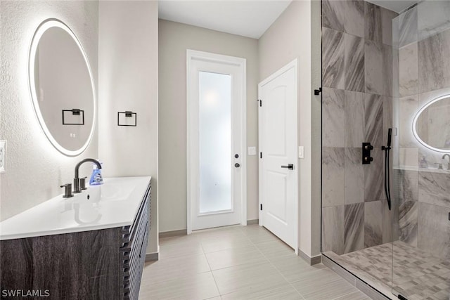 bathroom with tiled shower, vanity, and tile patterned flooring