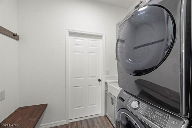 washroom featuring dark hardwood / wood-style floors, cabinets, and stacked washing maching and dryer