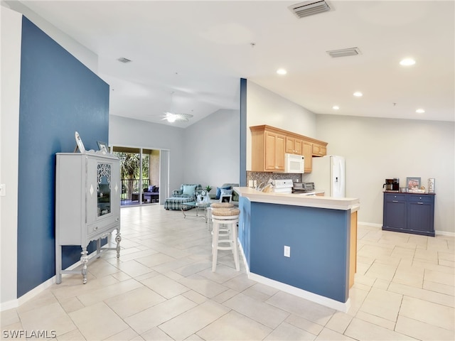 kitchen with ceiling fan, kitchen peninsula, vaulted ceiling, white appliances, and light brown cabinetry