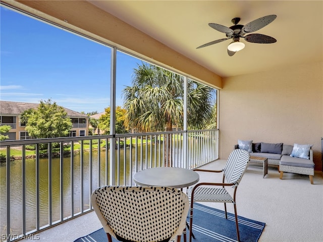 sunroom with ceiling fan and a water view