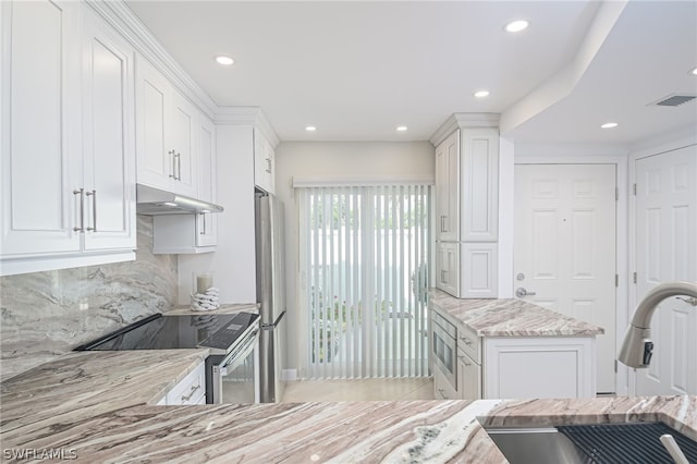 kitchen featuring backsplash, white cabinetry, stainless steel appliances, and light stone counters