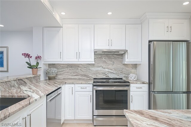 kitchen with decorative backsplash, light stone countertops, white cabinets, and appliances with stainless steel finishes