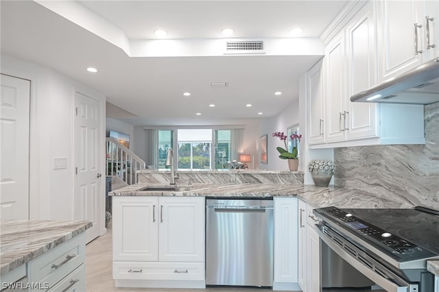 kitchen featuring backsplash, kitchen peninsula, white cabinets, and stainless steel appliances