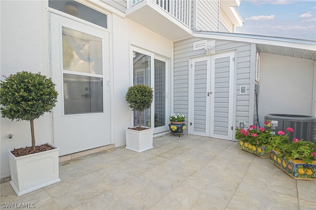 property entrance with cooling unit, a balcony, and a patio