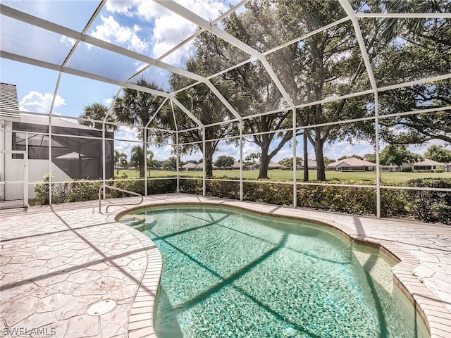 view of swimming pool featuring a patio and a lanai