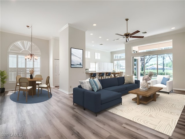 living room featuring ceiling fan with notable chandelier, ornamental molding, and hardwood / wood-style floors