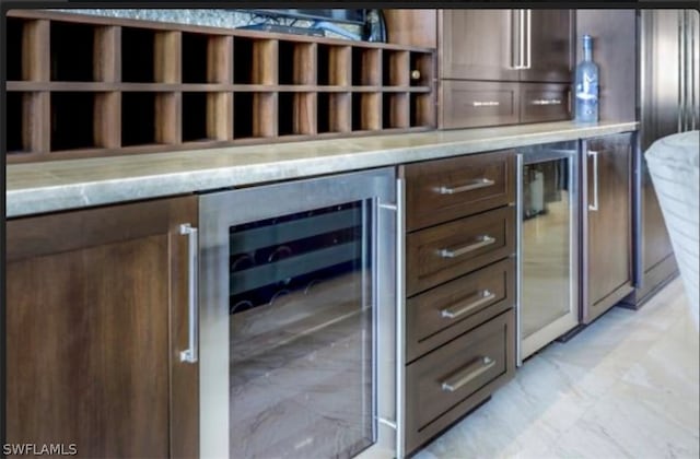 kitchen featuring wine cooler, light tile floors, and light stone countertops