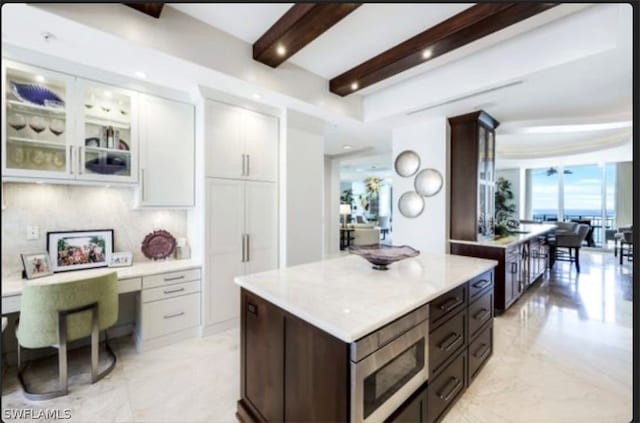 kitchen featuring stainless steel microwave, dark brown cabinets, beamed ceiling, white cabinets, and light tile floors