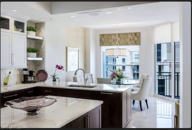 kitchen with dark brown cabinets, light tile floors, hanging light fixtures, sink, and white cabinetry