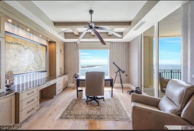 office area with a water view, plenty of natural light, ceiling fan, and light hardwood / wood-style flooring