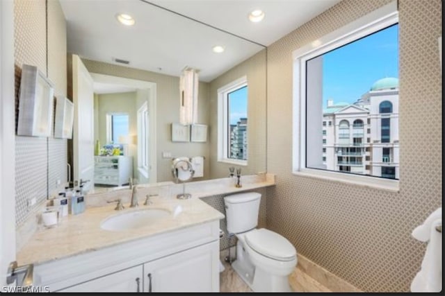 bathroom with tile walls, toilet, and vanity