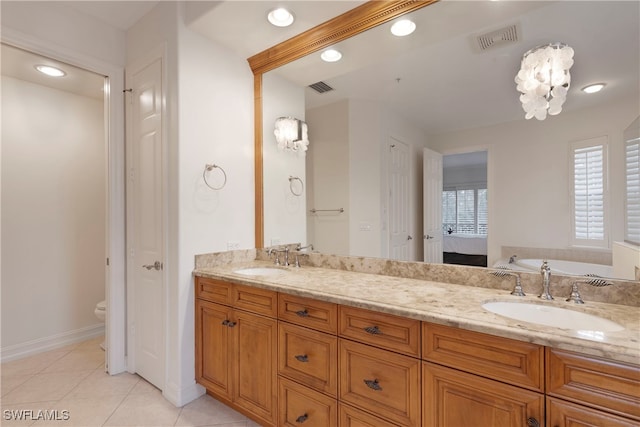 bathroom with tile patterned flooring, a bath, vanity, and toilet