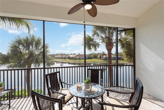 sunroom / solarium featuring a water view and ceiling fan