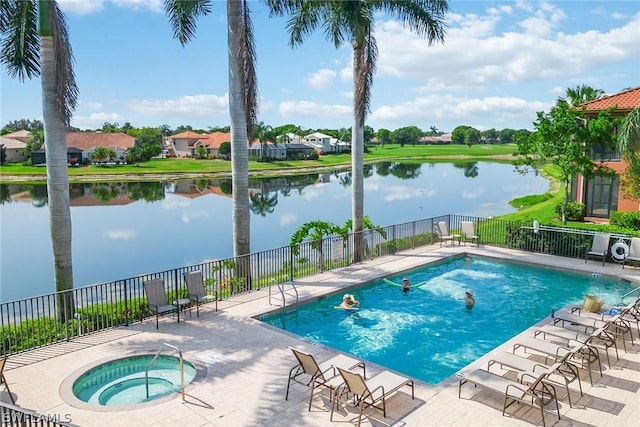 view of swimming pool with a patio area, a water view, and a hot tub