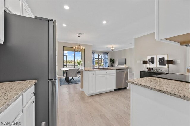 kitchen with appliances with stainless steel finishes, open floor plan, white cabinetry, and a sink