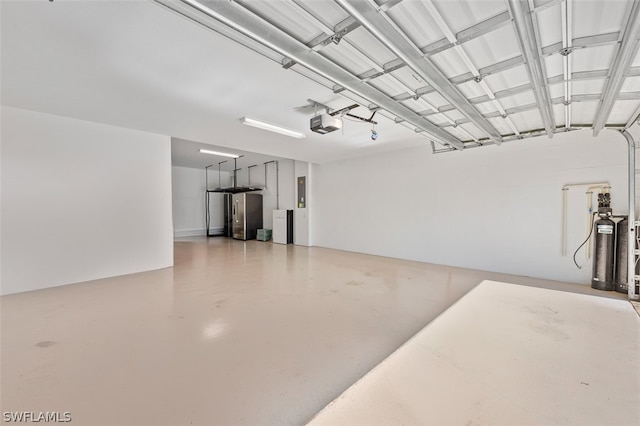 garage featuring a garage door opener, freestanding refrigerator, and electric panel