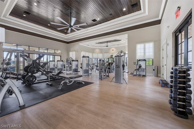 workout area with ornamental molding, a tray ceiling, wooden ceiling, and wood finished floors