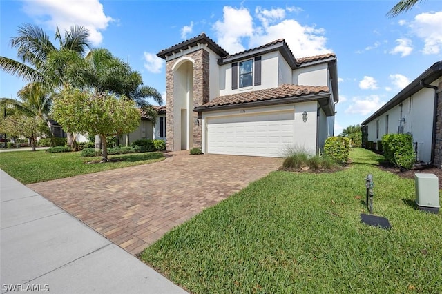 mediterranean / spanish house with a front yard, decorative driveway, a tiled roof, and stucco siding