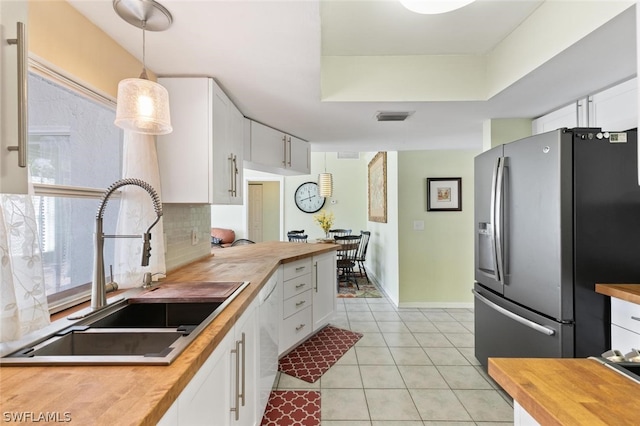 kitchen with wooden counters, sink, white cabinetry, and stainless steel refrigerator with ice dispenser