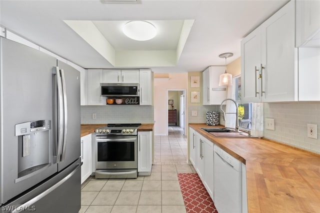 kitchen with white cabinetry, butcher block counters, decorative light fixtures, sink, and appliances with stainless steel finishes