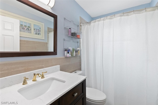 bathroom with vanity, toilet, a shower with curtain, and tile walls