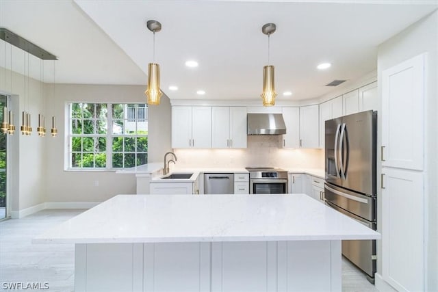 kitchen featuring stainless steel appliances, sink, white cabinets, and wall chimney range hood