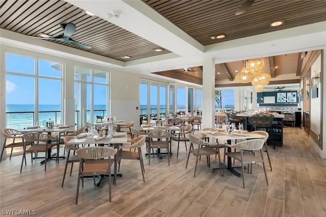 dining room featuring ceiling fan with notable chandelier, wooden ceiling, and a water view