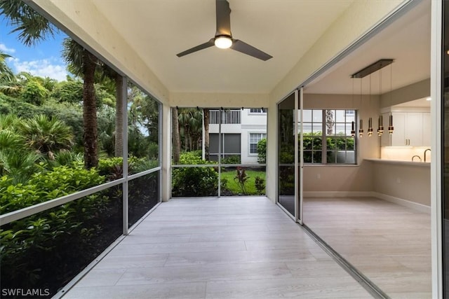 unfurnished sunroom with ceiling fan