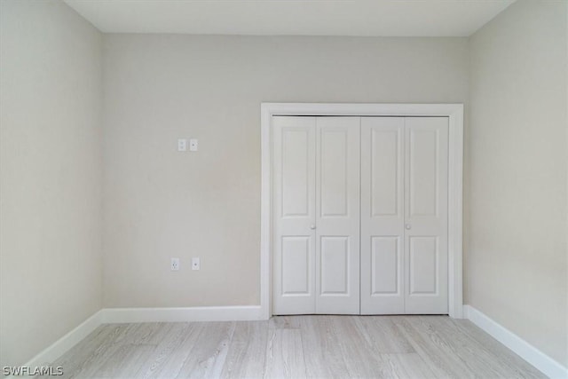 unfurnished bedroom featuring light wood-type flooring and a closet