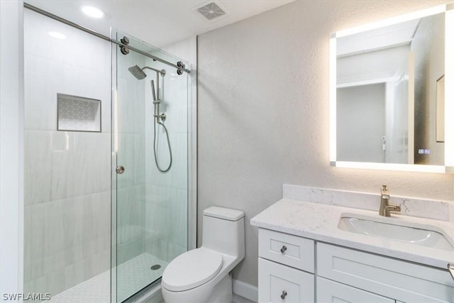 bathroom featuring a shower with door, toilet, and vanity