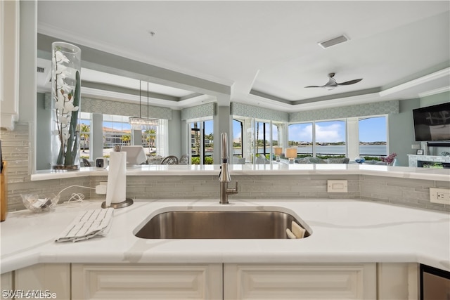 kitchen with ceiling fan, crown molding, decorative light fixtures, a raised ceiling, and sink