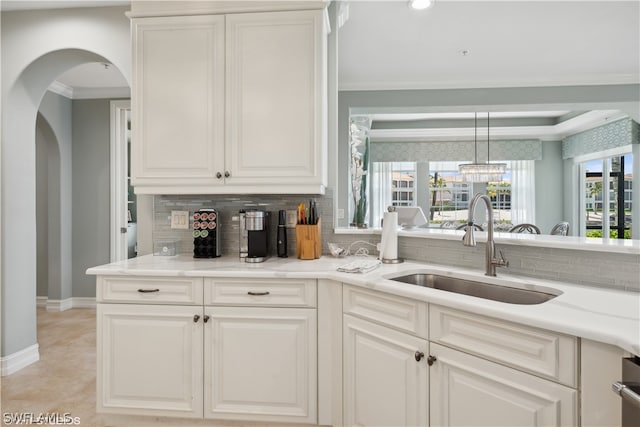 kitchen featuring decorative light fixtures, backsplash, light tile floors, sink, and white cabinets