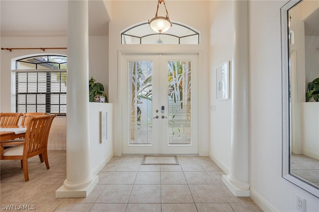 foyer with light tile floors, decorative columns, and french doors