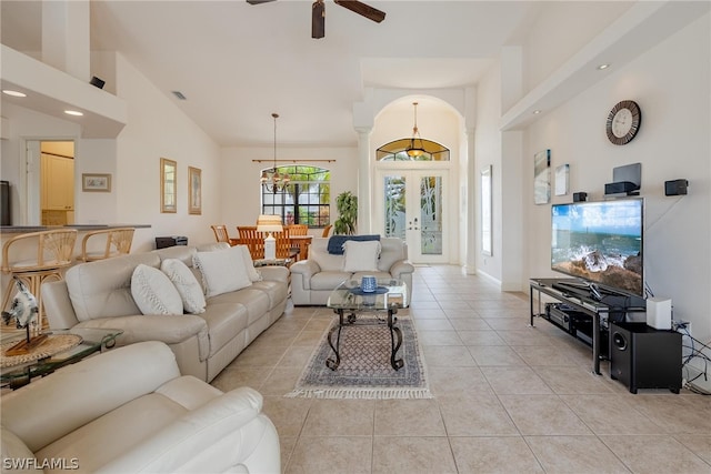 living room featuring high vaulted ceiling, french doors, light tile floors, and ceiling fan with notable chandelier