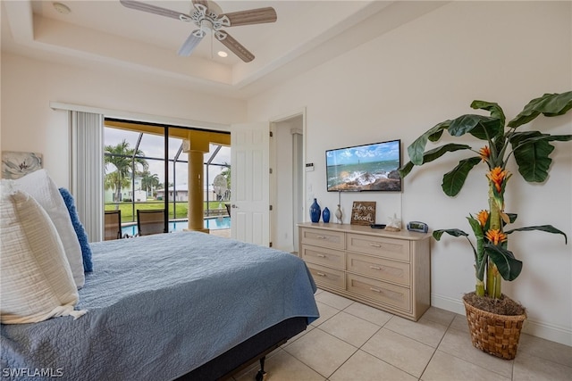 tiled bedroom with ceiling fan, a tray ceiling, and access to exterior