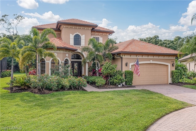 mediterranean / spanish-style home featuring a front lawn, stucco siding, driveway, and a garage