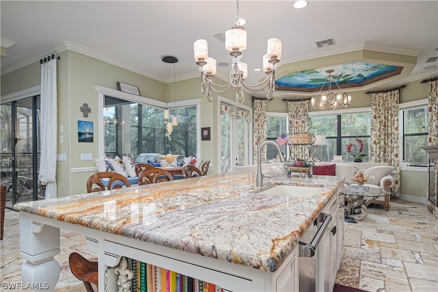 kitchen with an island with sink, ornamental molding, a wealth of natural light, and a chandelier