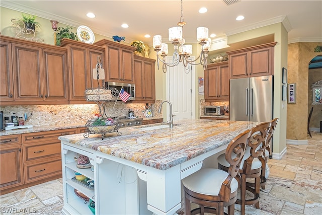 kitchen with appliances with stainless steel finishes, sink, tasteful backsplash, and a kitchen island with sink