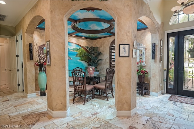 foyer entrance with a high ceiling, crown molding, a chandelier, and light tile floors