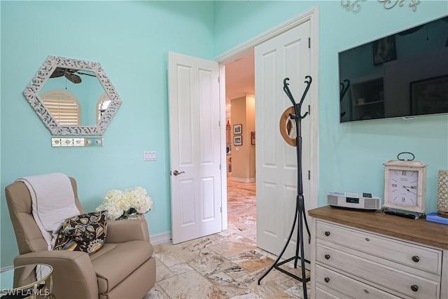 sitting room featuring baseboards and stone tile floors