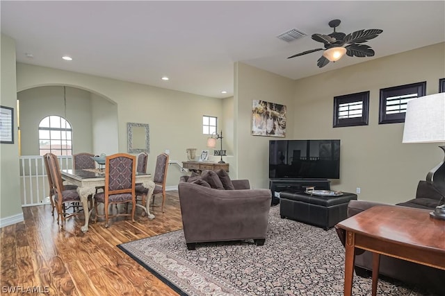 living area featuring recessed lighting, ceiling fan, visible vents, wood finished floors, and arched walkways
