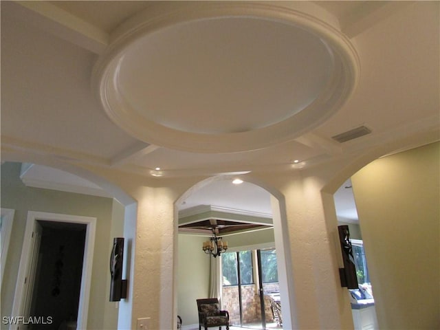 hall with an inviting chandelier, visible vents, arched walkways, a textured wall, and recessed lighting