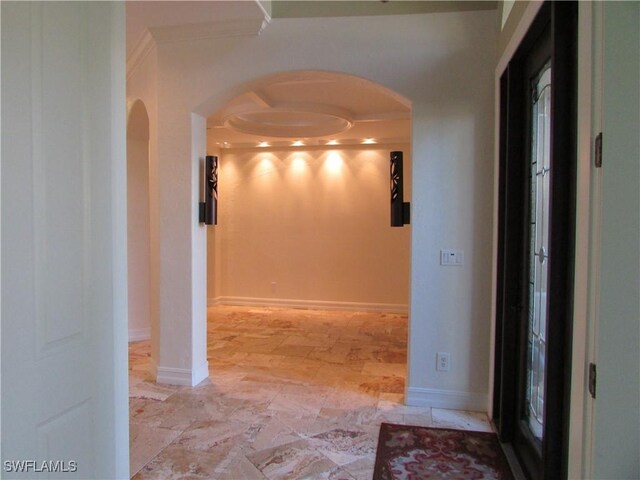 corridor with crown molding, arched walkways, and baseboards