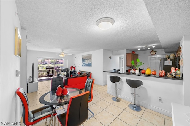 tiled dining room featuring ceiling fan, track lighting, and a textured ceiling