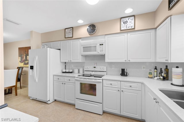 kitchen with white appliances, white cabinets, tasteful backsplash, and light tile floors