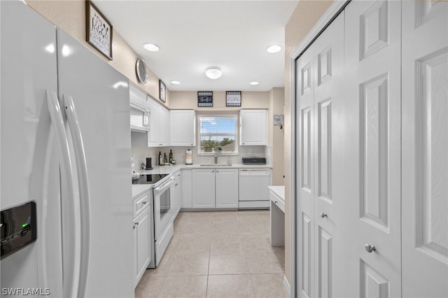 kitchen with sink, white cabinets, white appliances, and light tile floors