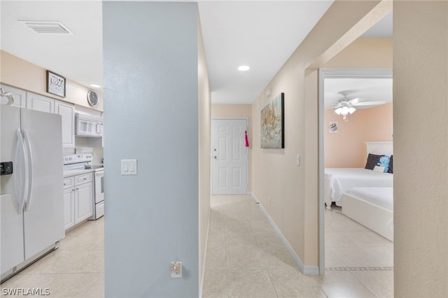 kitchen with white cabinets, white appliances, and light tile floors